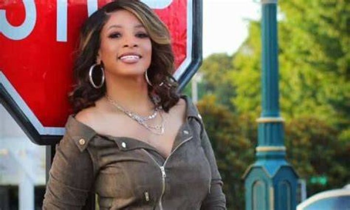 Kimmi Grant is smiling with her bald head in the picture.